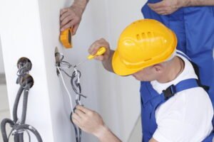 Un électricien change une prise murale