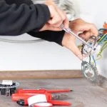 Un électricien change une prise électrique murale