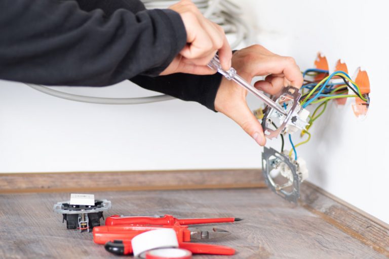 Un électricien change une prise électrique murale