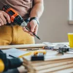 Un artisan tenant en main une perceuse sans-fil