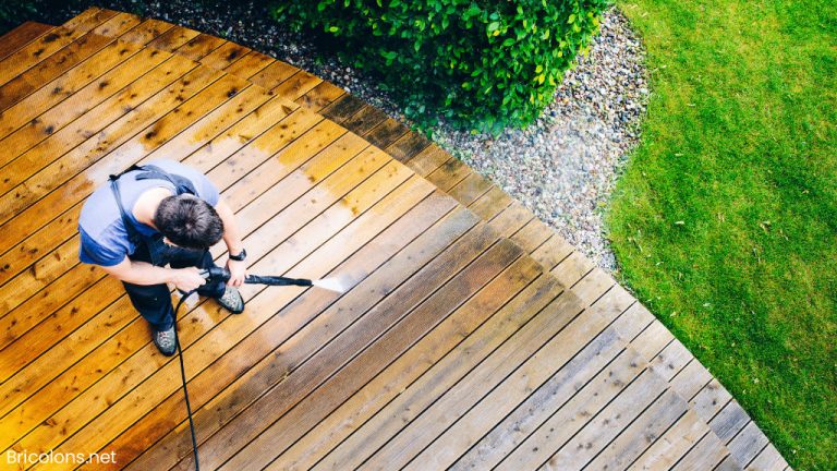 Homme nettoyant la terrasse avec un nettoyeur haute pression - nettoyeur haute pression sur la surface de la terrasse en bois