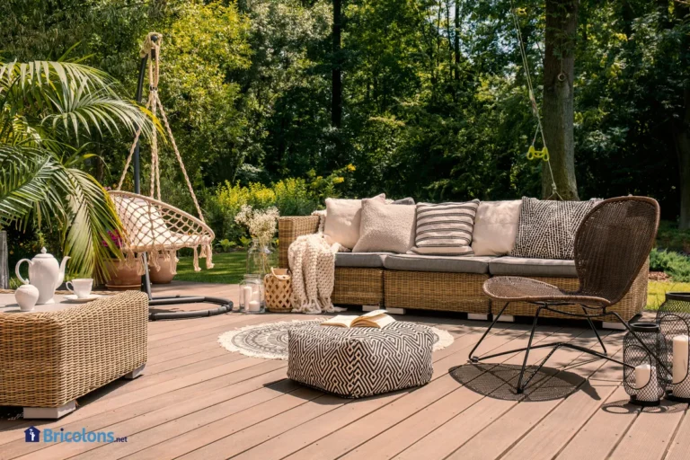 Un ensemble de patio en rotin comprenant un canapé, une table et une chaise sur une terrasse en bois dans le jardin ensoleillé.